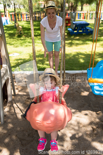 Image of mother and daughter swinging in the park