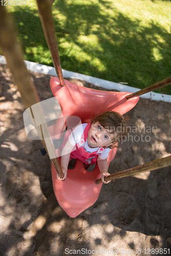 Image of little girl swinging  on a playground