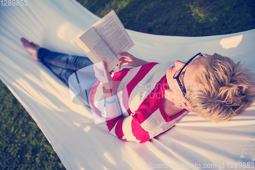 Image of woman reading a book while relaxing on hammock