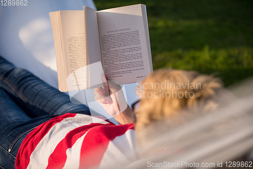 Image of woman reading a book while relaxing on hammock