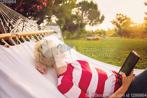 Image of woman using a tablet computer while relaxing on hammock