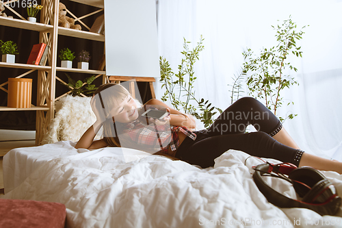 Image of Little girl using different gadgets at home