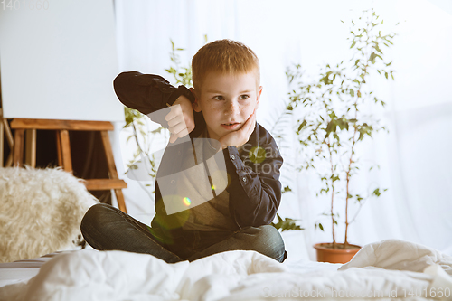 Image of Little boy using different gadgets at home