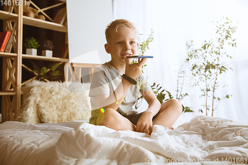 Image of Little boy using different gadgets at home