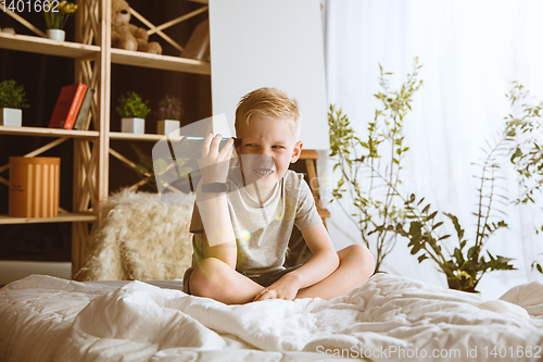 Image of Little boy using different gadgets at home