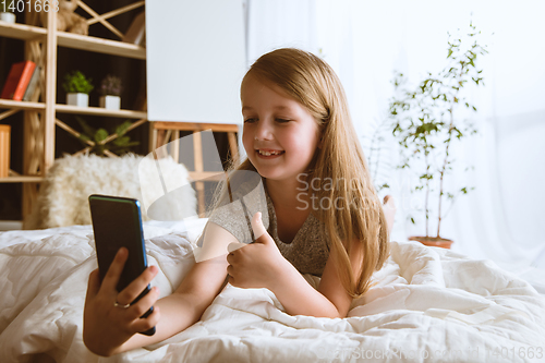 Image of Little girl using different gadgets at home