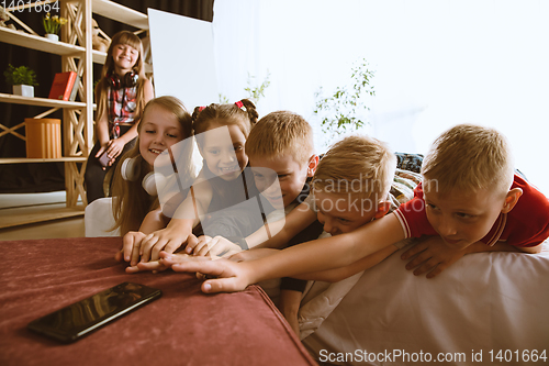 Image of Little boys and girls using different gadgets at home