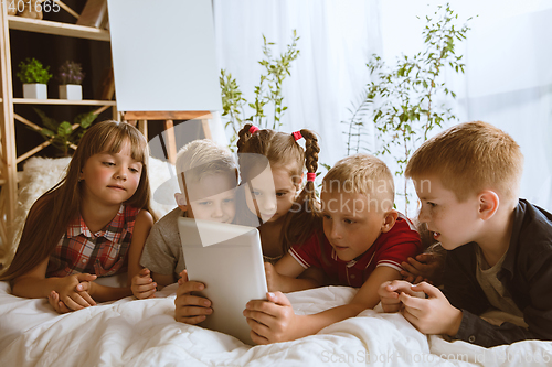 Image of Little boys and girls using different gadgets at home