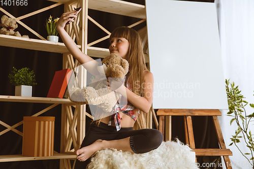 Image of Little girl using different gadgets at home