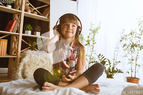 Image of Little girl using different gadgets at home