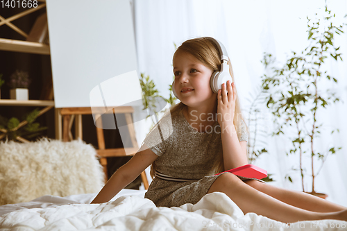 Image of Little girl using different gadgets at home