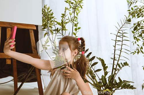 Image of Little girl using different gadgets at home