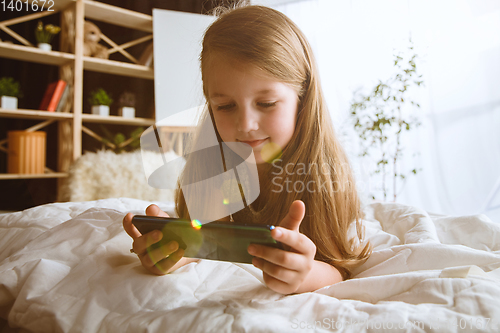 Image of Little girl using different gadgets at home