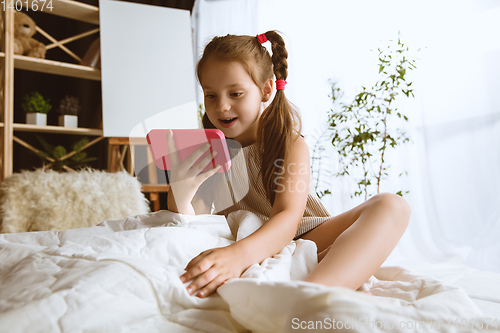 Image of Little girl using different gadgets at home