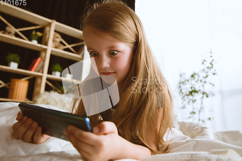 Image of Little girl using different gadgets at home