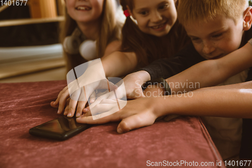 Image of Little boys and girls using different gadgets at home