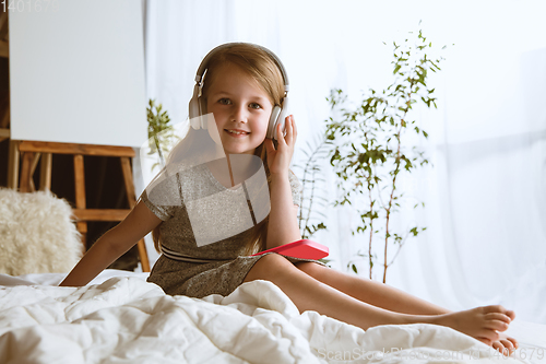 Image of Little girl using different gadgets at home