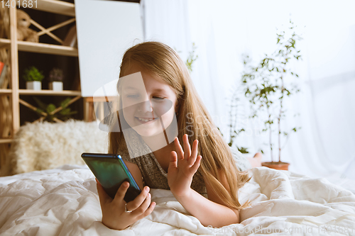 Image of Little girl using different gadgets at home