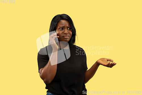 Image of Young african woman isolated on yellow studio background, facial expression