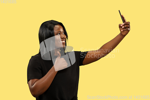 Image of Young african woman isolated on yellow studio background, facial expression