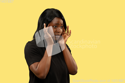 Image of Young african woman isolated on yellow studio background, facial expression
