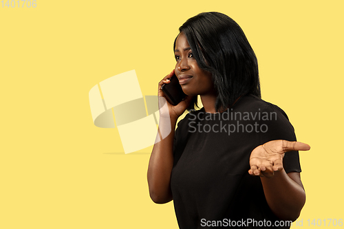 Image of Young african woman isolated on yellow studio background, facial expression