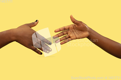 Image of Close up shot of human holding hands isolated on yellow studio background.