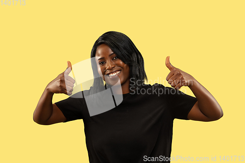 Image of Young african woman isolated on yellow studio background, facial expression