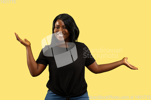 Image of Young african woman isolated on yellow studio background, facial expression