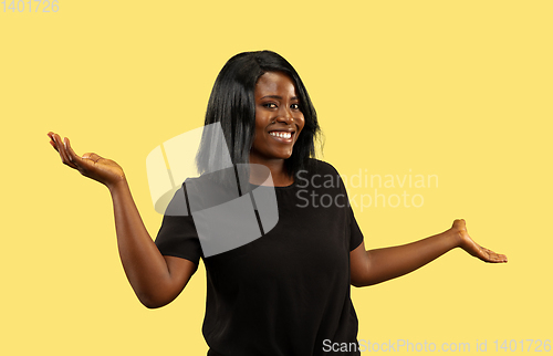 Image of Young african woman isolated on yellow studio background, facial expression