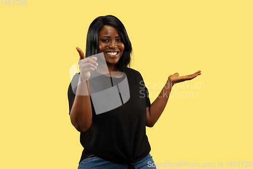 Image of Young african woman isolated on yellow studio background, facial expression