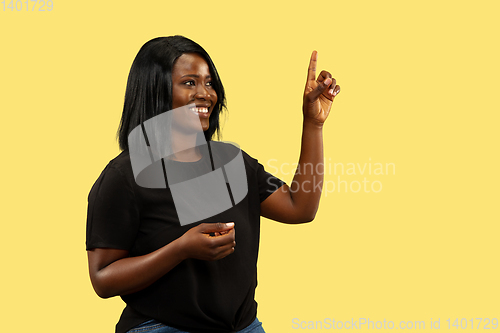 Image of Young african woman isolated on yellow studio background, facial expression