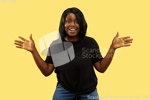 Image of Young african woman isolated on yellow studio background, facial expression