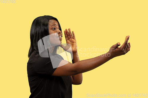 Image of Young african woman isolated on yellow studio background, facial expression