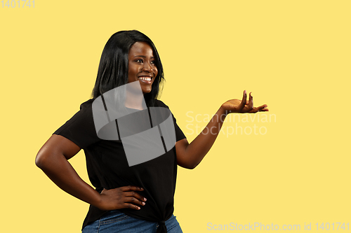 Image of Young african woman isolated on yellow studio background, facial expression