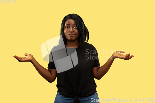 Image of Young african woman isolated on yellow studio background, facial expression