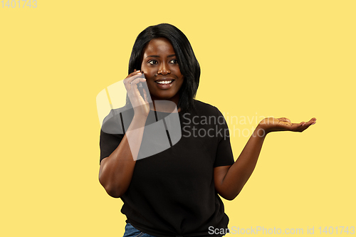 Image of Young african woman isolated on yellow studio background, facial expression