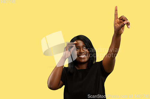 Image of Young african woman isolated on yellow studio background, facial expression