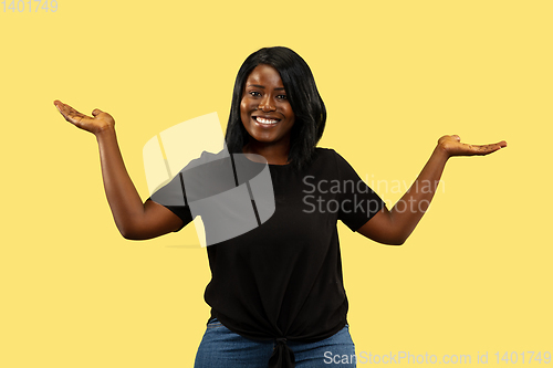 Image of Young african woman isolated on yellow studio background, facial expression