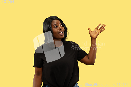 Image of Young african woman isolated on yellow studio background, facial expression