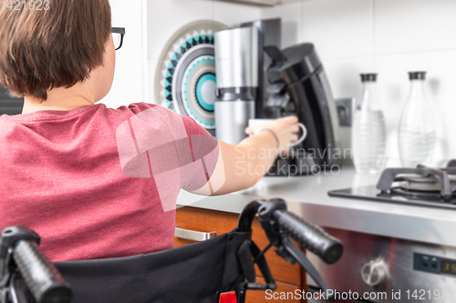 Image of disabled woman getting coffee in the kitchen