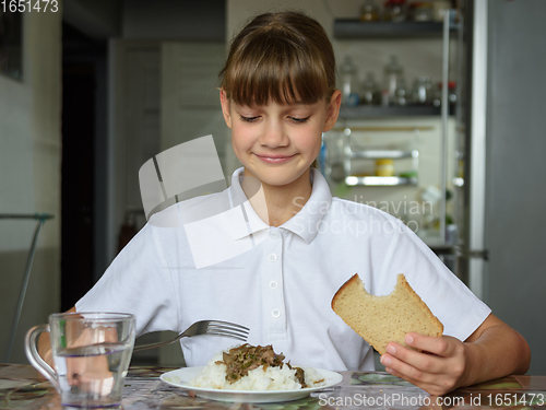 Image of The girl is having dinner at the table, she looked at the food with appetite