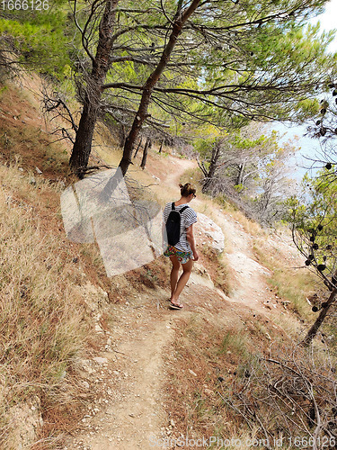 Image of Young active feamle tourist wearing small backpack walking on co