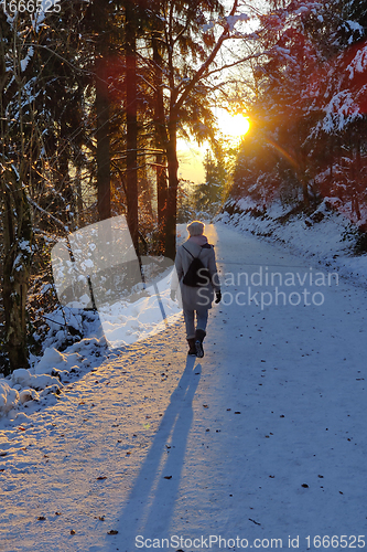 Image of Woman hiking on snow in white winter forest berore the sunset. Recreation and healthy lifestyle outdoors in nature