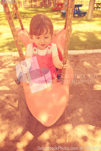 Image of little girl swinging  on a playground