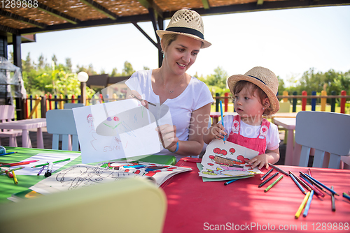 Image of mom and little daughter drawing a colorful pictures