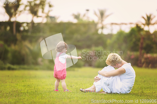 Image of mother and little daughter playing at backyard