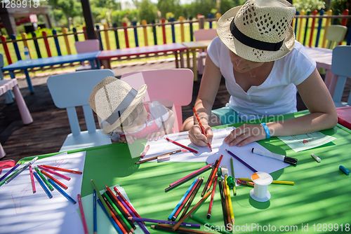 Image of mom and little daughter drawing a colorful pictures