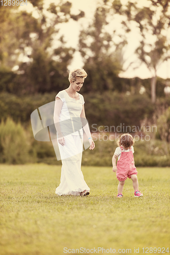 Image of mother and little daughter playing at backyard