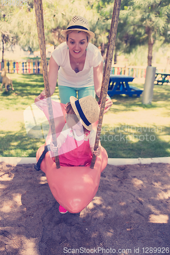 Image of mother and daughter swinging in the park